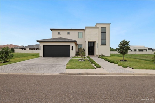 contemporary house with a front lawn, driveway, an attached garage, and stucco siding