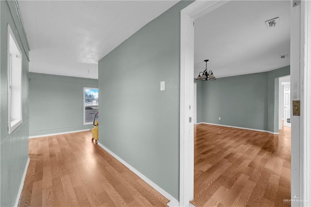 hall featuring an inviting chandelier and light hardwood / wood-style flooring