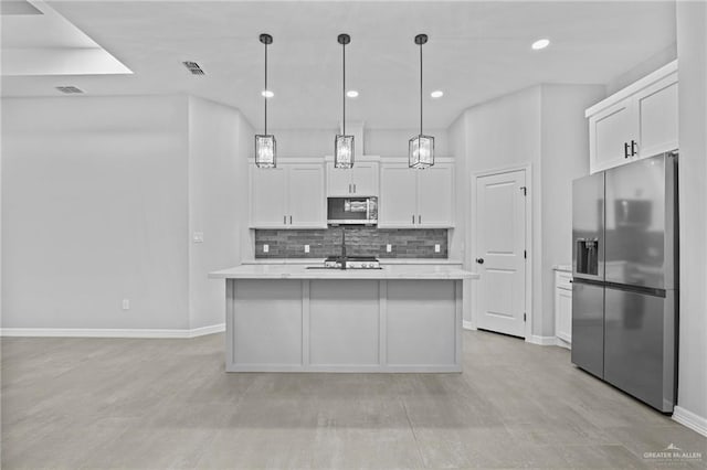 kitchen with white cabinetry, decorative light fixtures, decorative backsplash, a center island with sink, and appliances with stainless steel finishes