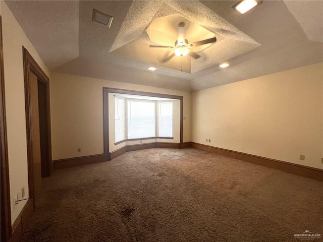 carpeted spare room with ceiling fan, a textured ceiling, and a tray ceiling