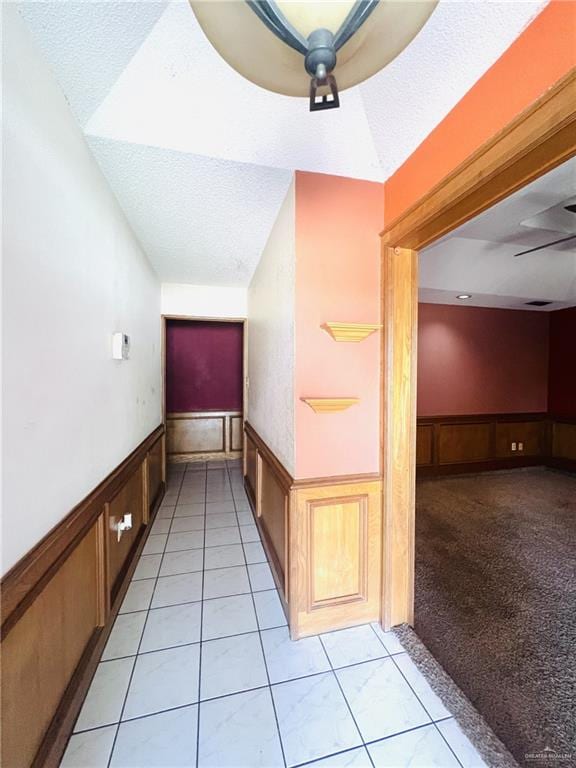 hallway featuring light colored carpet and a textured ceiling