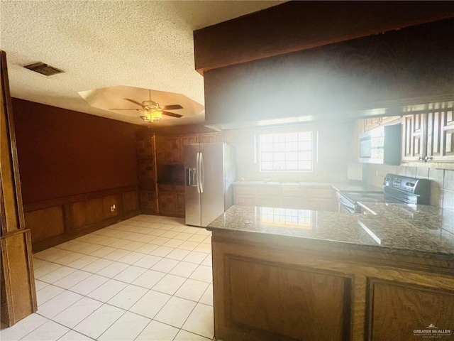 4407 Alejandro St, Mission, TX 78573 - kitchen with white appliances, a ceiling fan, a peninsula, light tile patterned floors, and wainscoting
