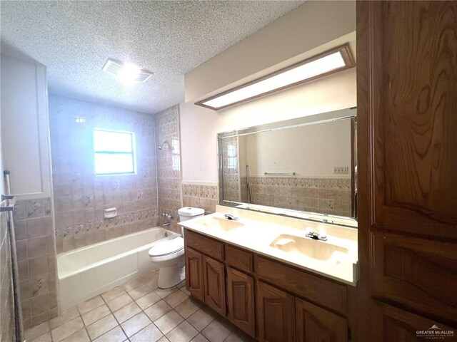 full bathroom with tile patterned flooring, vanity, tile walls, and a textured ceiling