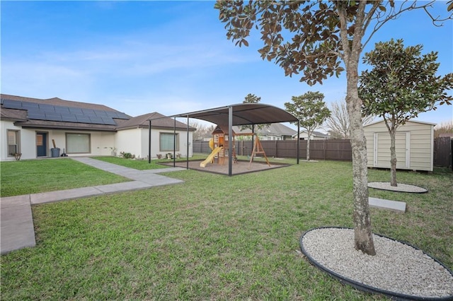 view of yard with a storage shed, a playground, fence private yard, and an outbuilding