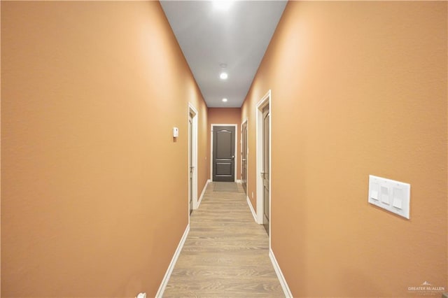 hall with light wood-type flooring and baseboards