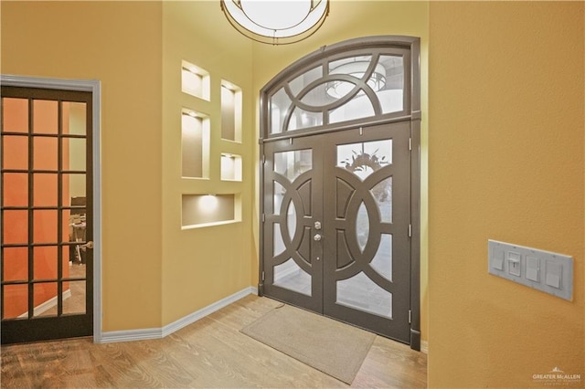 foyer with french doors, wood finished floors, and baseboards