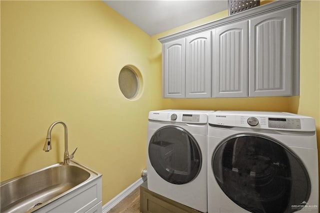 laundry area featuring cabinet space, baseboards, a sink, and independent washer and dryer