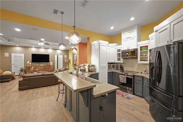 kitchen featuring stainless steel appliances, visible vents, a sink, a peninsula, and a kitchen bar