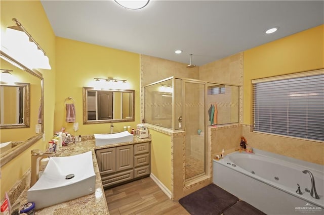 bathroom featuring a stall shower, a tub with jets, wood finished floors, vanity, and recessed lighting