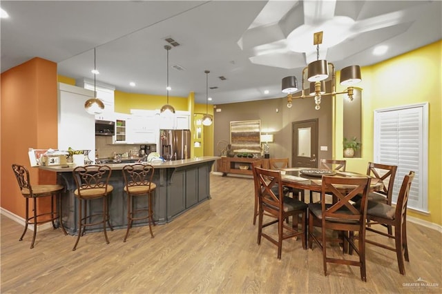 kitchen with a peninsula, light wood finished floors, stainless steel refrigerator with ice dispenser, and white cabinets