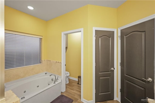 full bathroom featuring baseboards, toilet, wood finished floors, a whirlpool tub, and recessed lighting