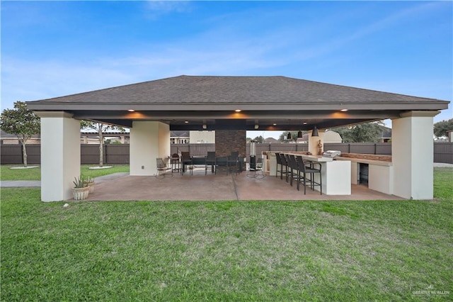 rear view of property featuring fence, a gazebo, and a lawn