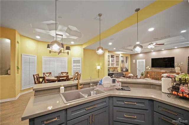 kitchen with recessed lighting, a sink, open floor plan, gray cabinets, and a tray ceiling