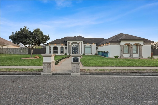 view of front of house with fence, a front lawn, and stucco siding