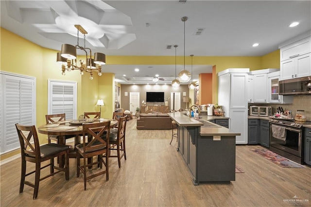 kitchen featuring a peninsula, a sink, visible vents, appliances with stainless steel finishes, and tasteful backsplash