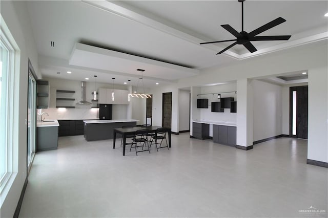 dining space with ceiling fan, a raised ceiling, and sink