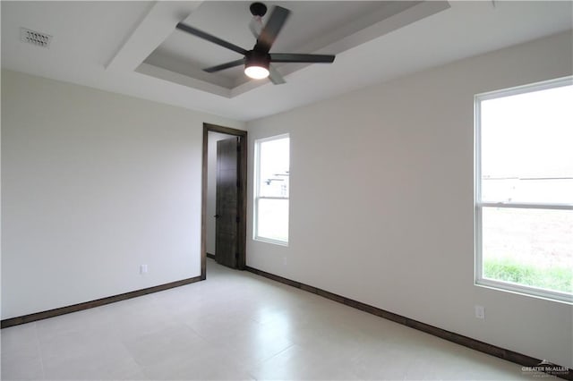 empty room with a raised ceiling and ceiling fan