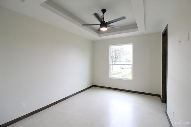 unfurnished room with ceiling fan and a raised ceiling