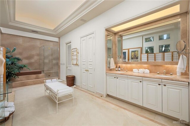 bathroom featuring a tray ceiling, tile patterned floors, vanity, and ornamental molding