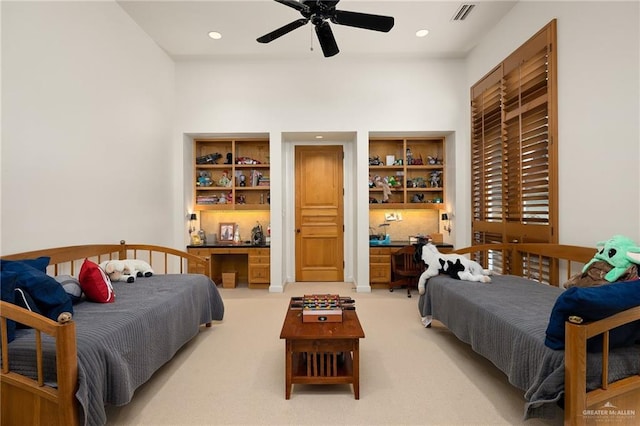 carpeted bedroom with built in desk and ceiling fan