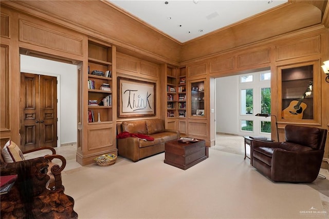 sitting room featuring light carpet, a high ceiling, and built in features