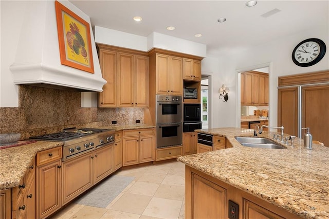 kitchen featuring light stone counters, sink, custom range hood, and stainless steel appliances