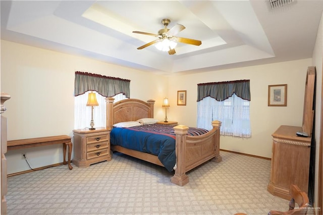 carpeted bedroom with a raised ceiling and ceiling fan