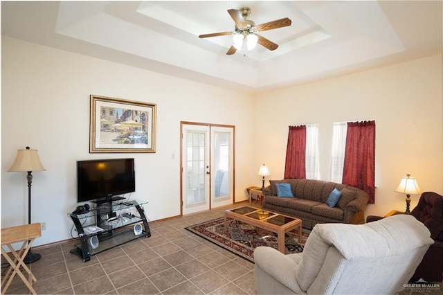 tiled living room featuring french doors, a raised ceiling, and ceiling fan