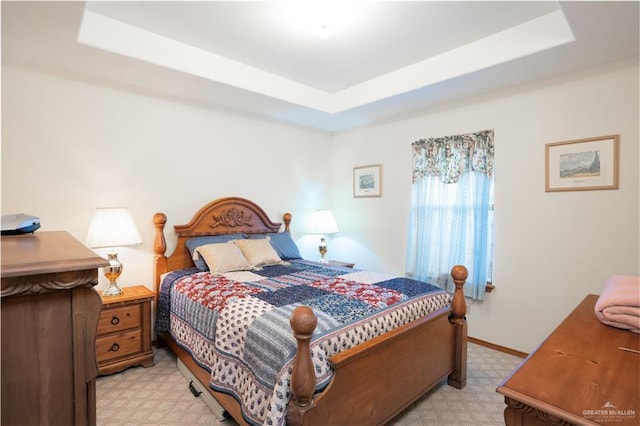 bedroom with light carpet and a tray ceiling