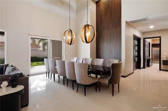 dining room with an inviting chandelier, a towering ceiling, and light tile patterned floors