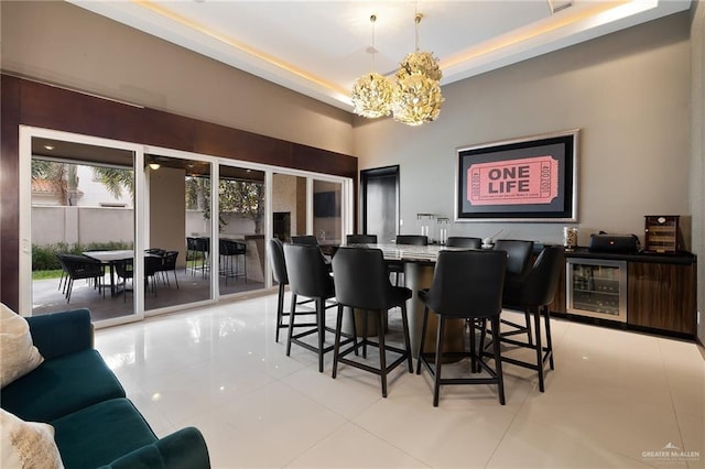 tiled dining room featuring a notable chandelier, a tray ceiling, and beverage cooler