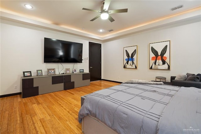 bedroom featuring a raised ceiling and light wood-type flooring