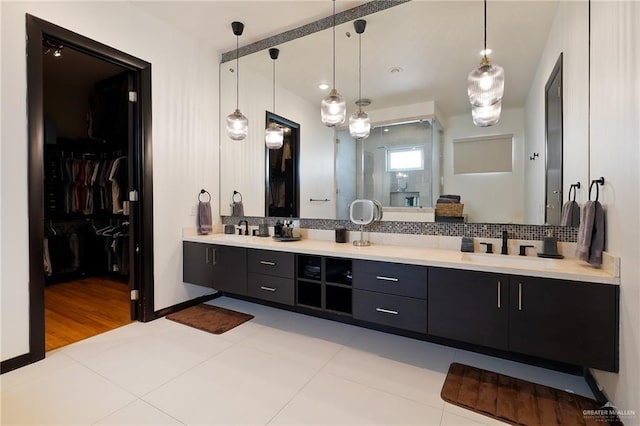 bathroom featuring tile patterned flooring, vanity, backsplash, and a shower with shower door