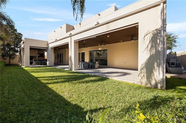 rear view of property with a yard, a patio area, and ceiling fan