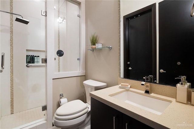 bathroom featuring a shower with door, vanity, and toilet