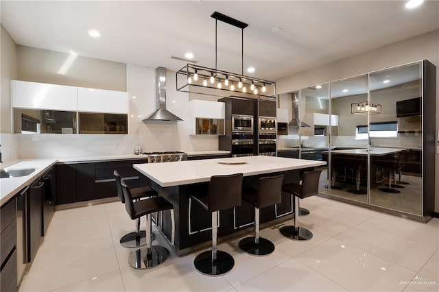 kitchen featuring a center island, a breakfast bar area, wall chimney range hood, and decorative light fixtures