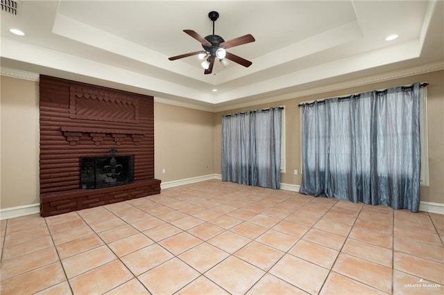 unfurnished living room featuring ceiling fan, light tile patterned floors, a fireplace, and a tray ceiling