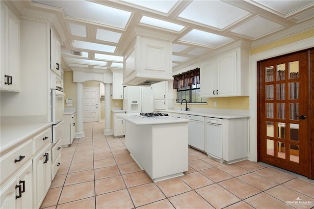 kitchen featuring coffered ceiling, white appliances, light tile patterned floors, a center island, and white cabinetry