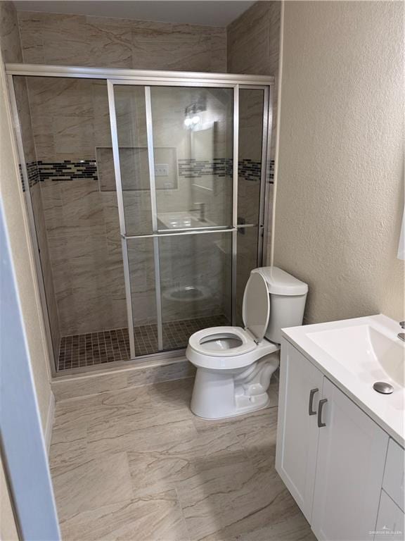 bathroom with vanity, toilet, and a shower with shower door