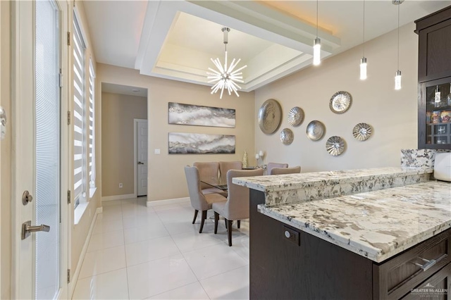 kitchen featuring light stone countertops, light tile patterned floors, pendant lighting, and an inviting chandelier