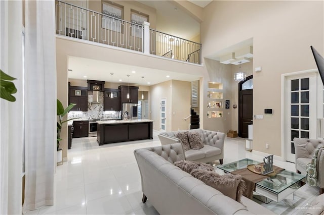 living room featuring light tile patterned floors, a towering ceiling, and sink