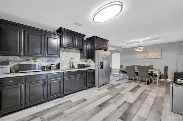 kitchen featuring visible vents, decorative backsplash, a raised ceiling, wood tiled floor, and stainless steel appliances