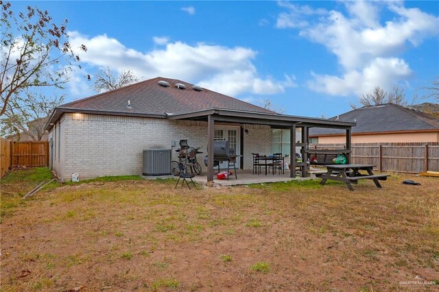 rear view of property featuring a fenced backyard, brick siding, a lawn, and central air condition unit