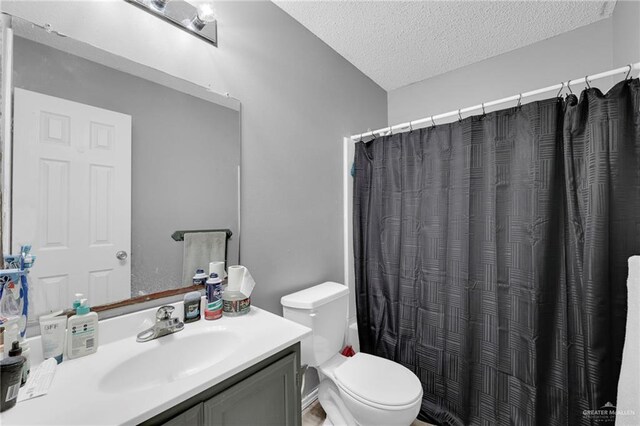 full bathroom featuring a textured ceiling, toilet, vanity, and curtained shower