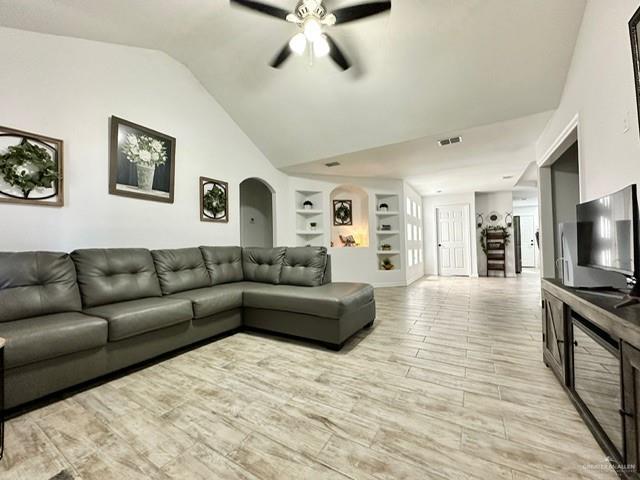 712 Bridget St, Weslaco, TX 78596 - living room with a ceiling fan, vaulted ceiling, built in shelves, arched walkways, and light wood-style floors
