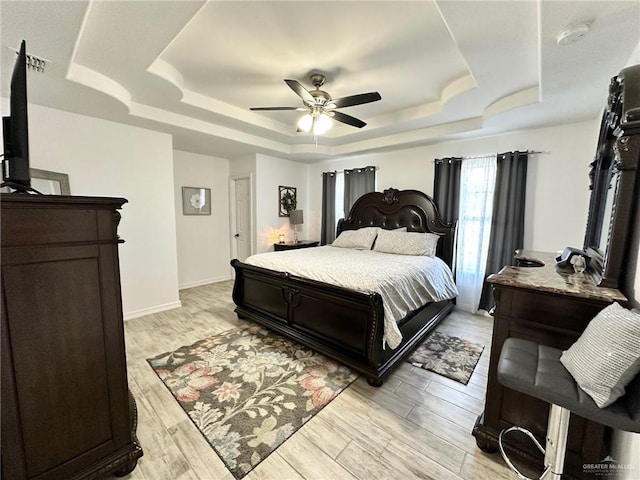712 Bridget St, Weslaco, TX 78596 - bedroom with a tray ceiling, a ceiling fan, and light wood-style flooring