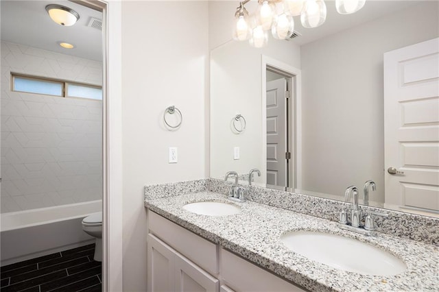 full bathroom with visible vents, a sink, toilet, and double vanity