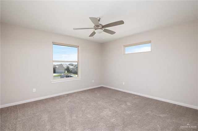 carpeted empty room featuring a ceiling fan, baseboards, and a wealth of natural light