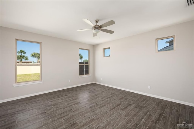 unfurnished room with a ceiling fan, visible vents, dark wood finished floors, and baseboards