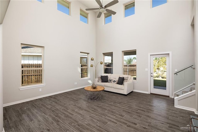 unfurnished room featuring stairs, dark wood finished floors, a ceiling fan, and baseboards